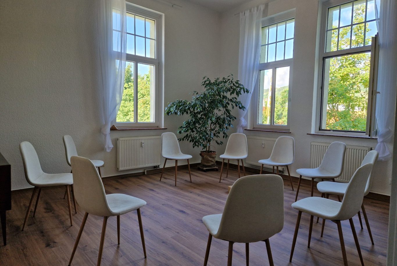 Zwei weiße Stühle mit Holzbeinen neben einem kleinen Tisch auf einem Teppich.